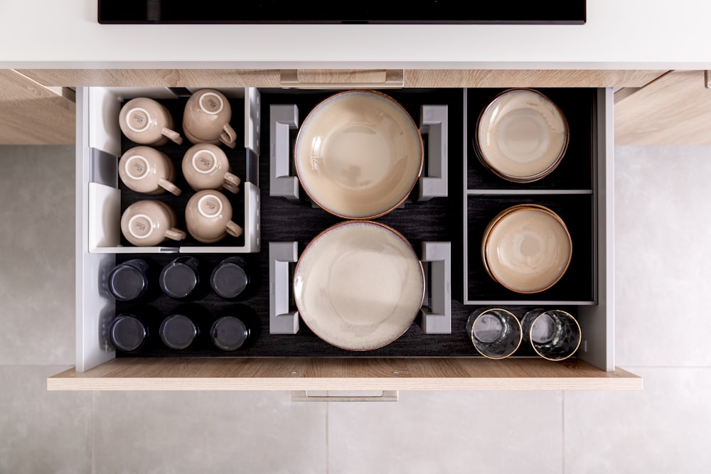 a drawer with dishes and cups inside of it
