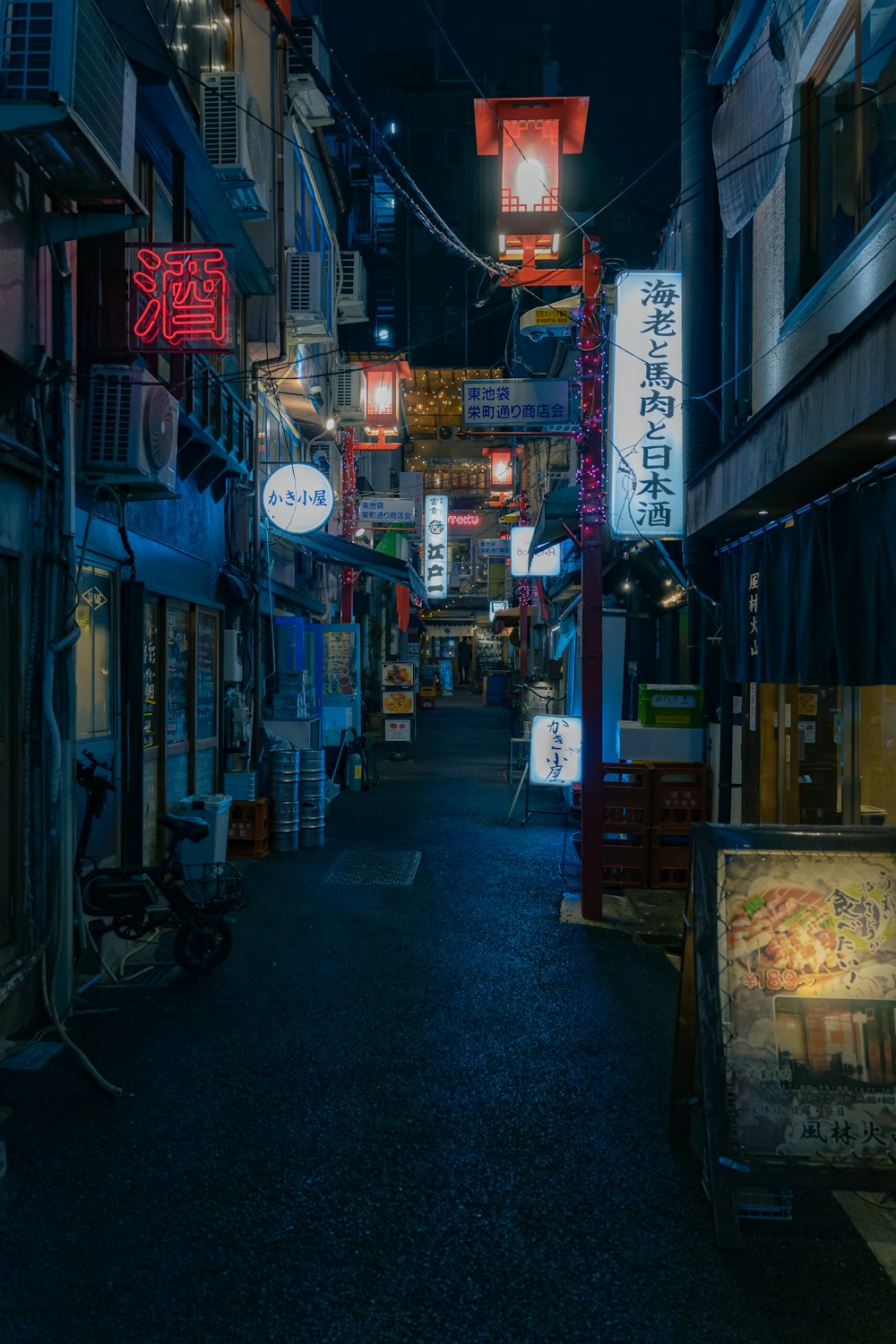 a dark alley with neon signs hanging from it's sides