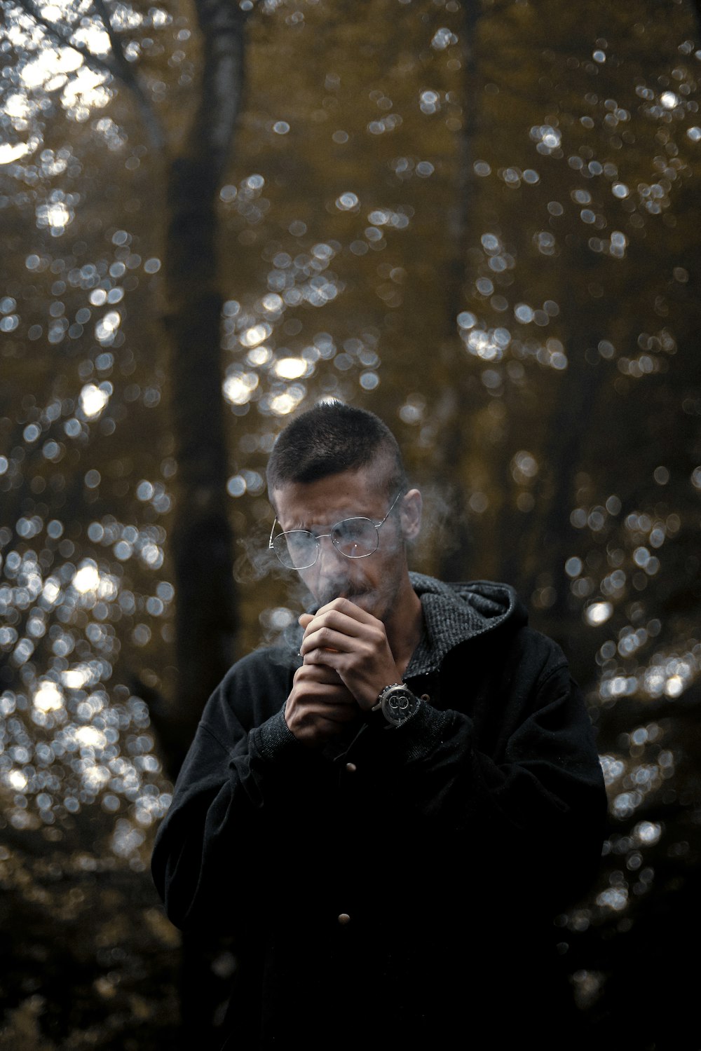 a man standing in front of a forest smoking a cigarette
