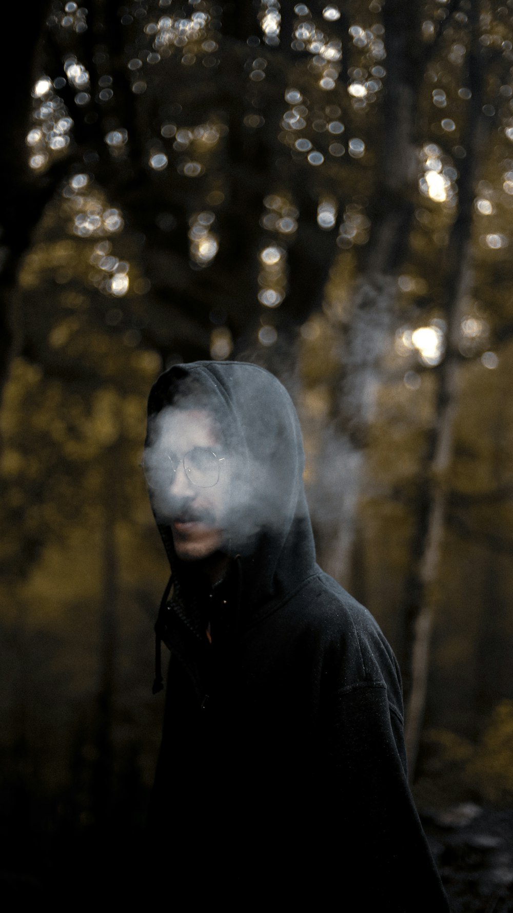 a man in a hooded jacket standing in a forest