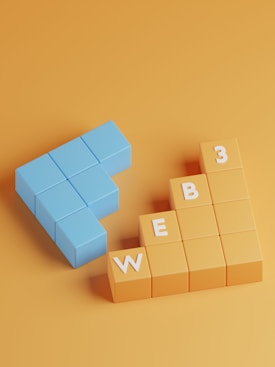 A three-dimensional arrangement of blocks on a solid orange background. The blue blocks are shaped like an arrow pointing left, and the orange blocks are stacked like steps with white letters spelling 'WEB 3'.