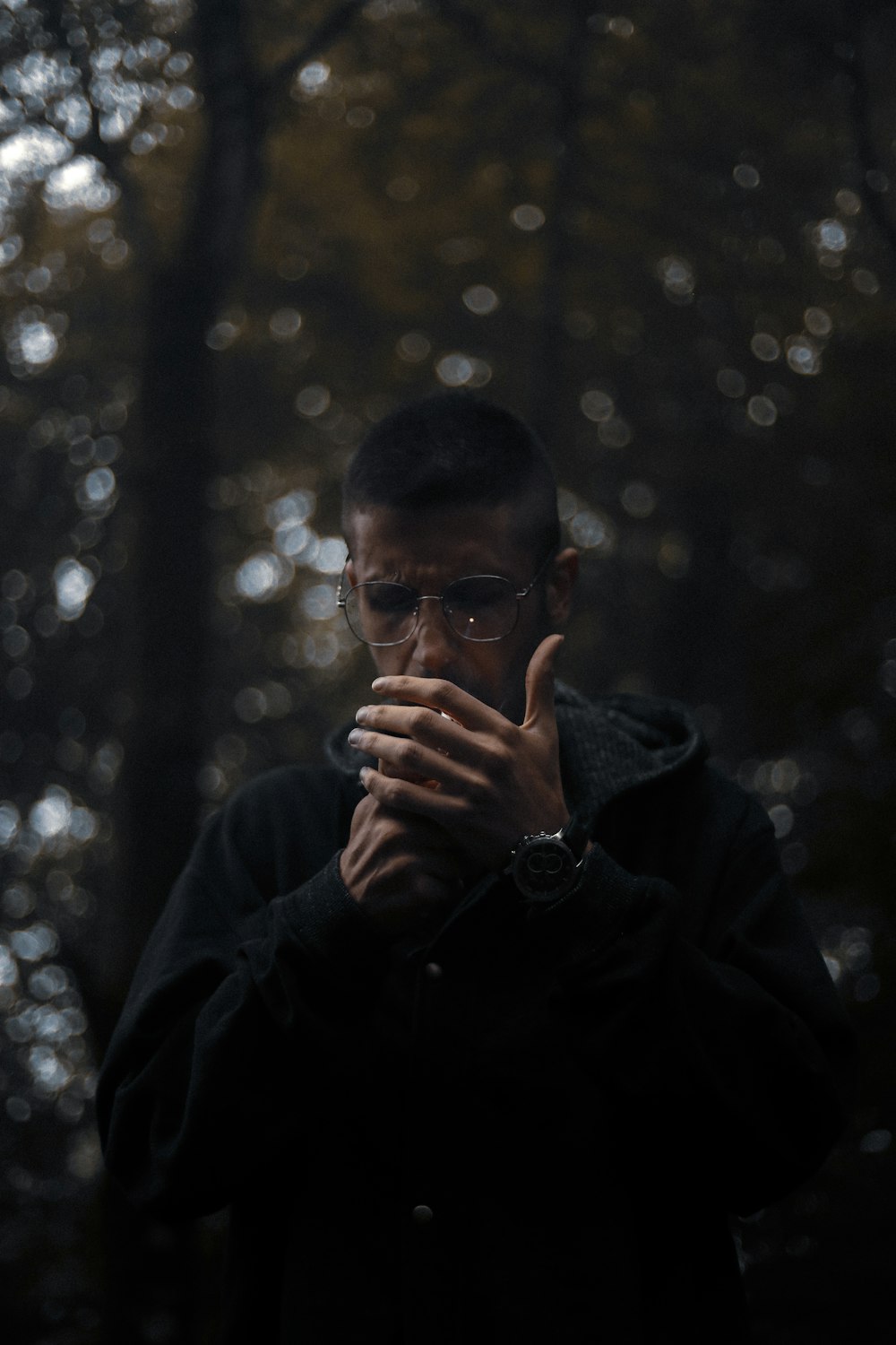 a man standing in front of a forest holding his hands together