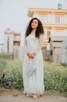 Woman wearing a flowing dress and holding a stylish handbag outdoors.