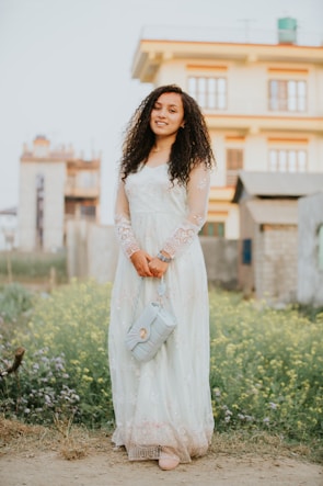 Woman wearing a flowing dress and holding a stylish handbag outdoors.