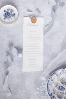Close-up of a historically accurate menu card alongside vintage silverware and a flickering candle.