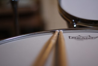 Close-up of vintage drumsticks crossed over a faded drumhead, evoking decades of musical history.