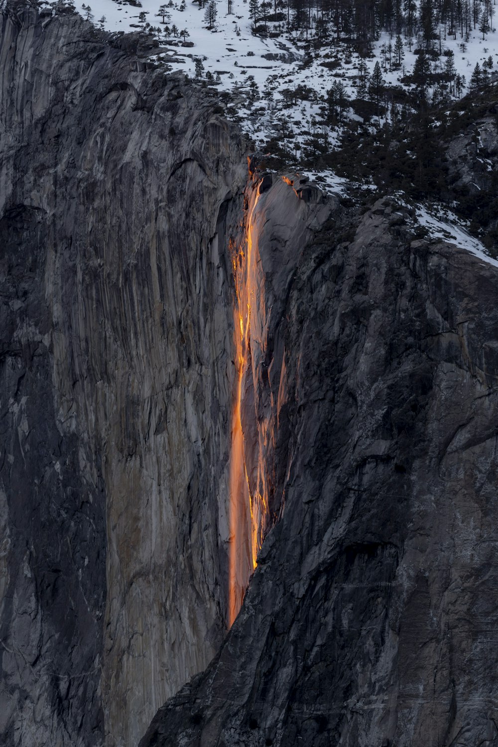 a waterfall is lit up on a snowy mountain