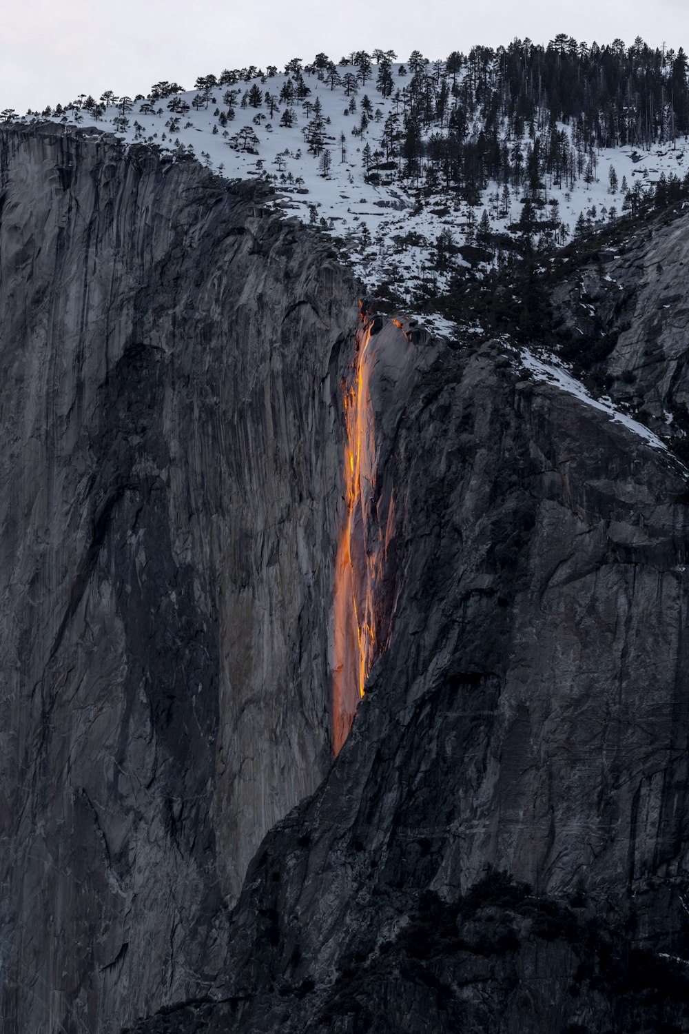 a tall mountain with a waterfall flowing down it's side