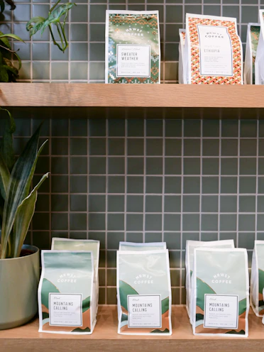 A vibrant display of coffee bags with traditional Mexican patterns on a wooden shelf.