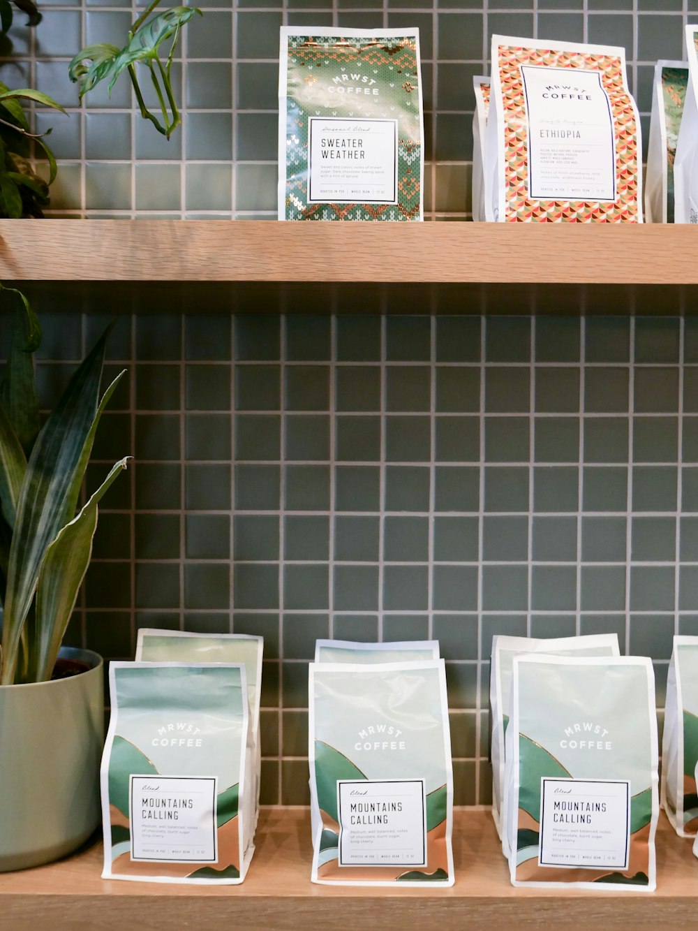 a shelf filled with coffee bags next to a potted plant