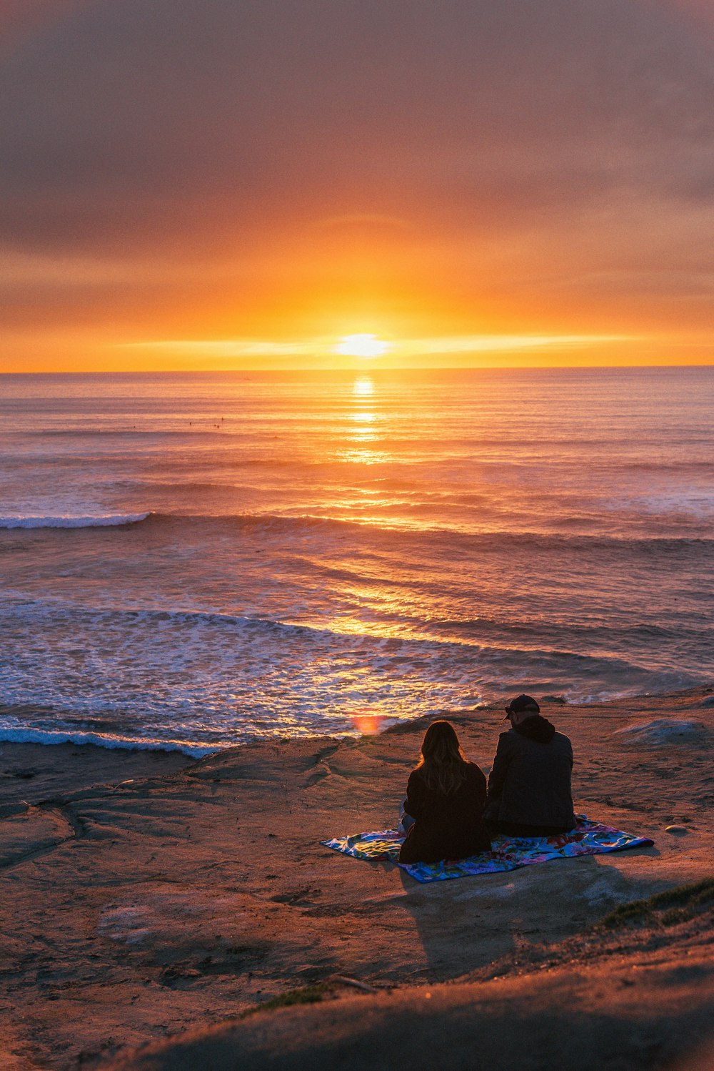 a couple of people sitting on top of a sandy beach