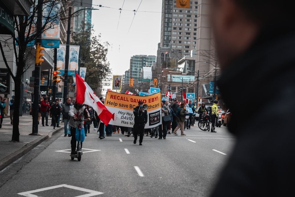 a group of people walking down a street holding signs