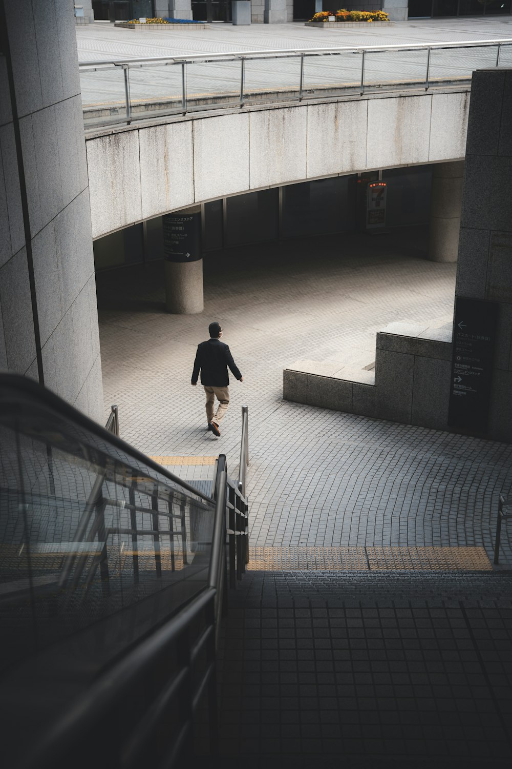 a man walking down a walkway next to an escalator