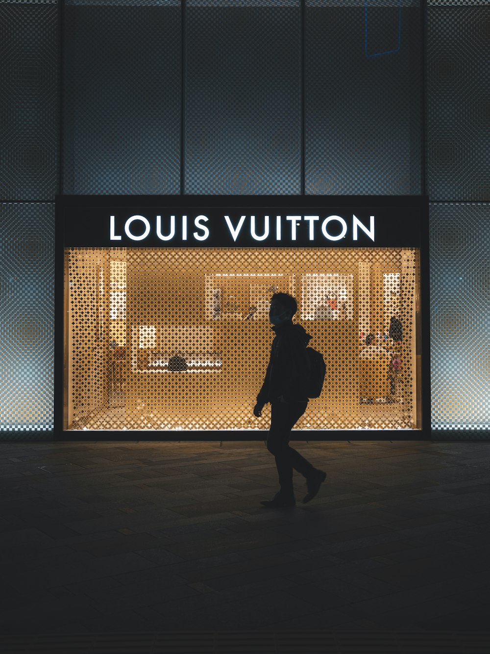 a person walking in front of a louis vuitton store