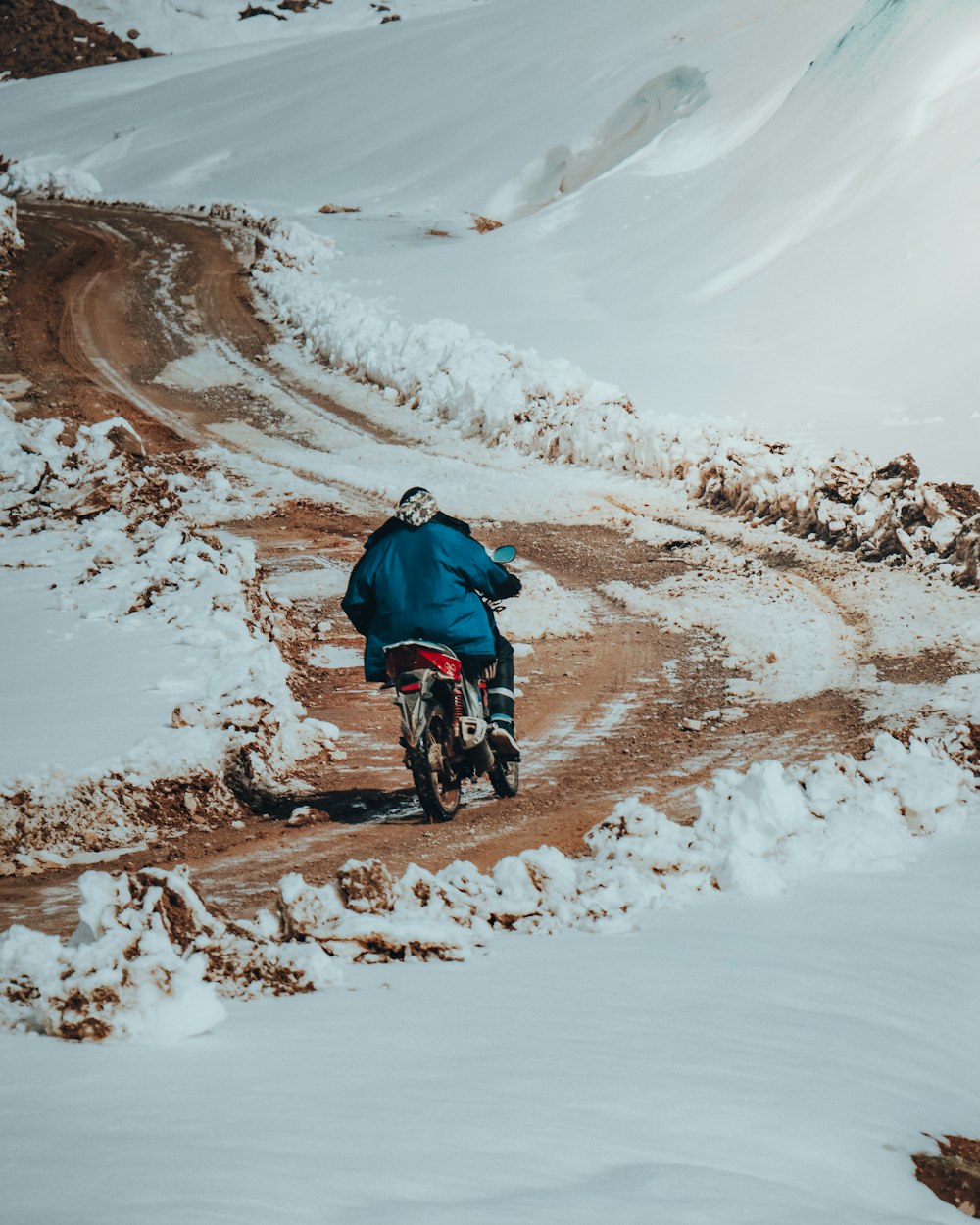 a man riding a motorcycle down a snow covered road