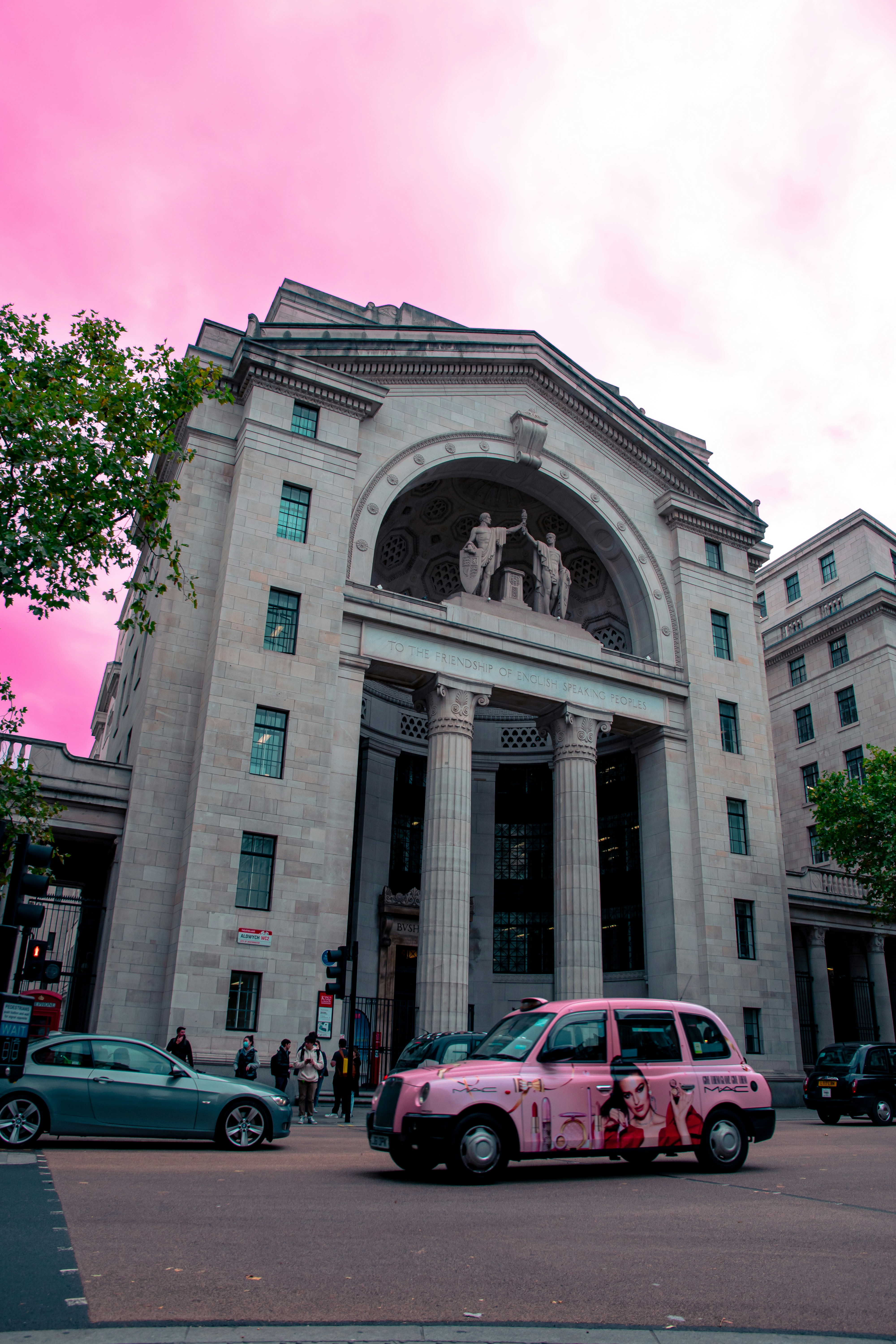 a pink car parked in front of a large building