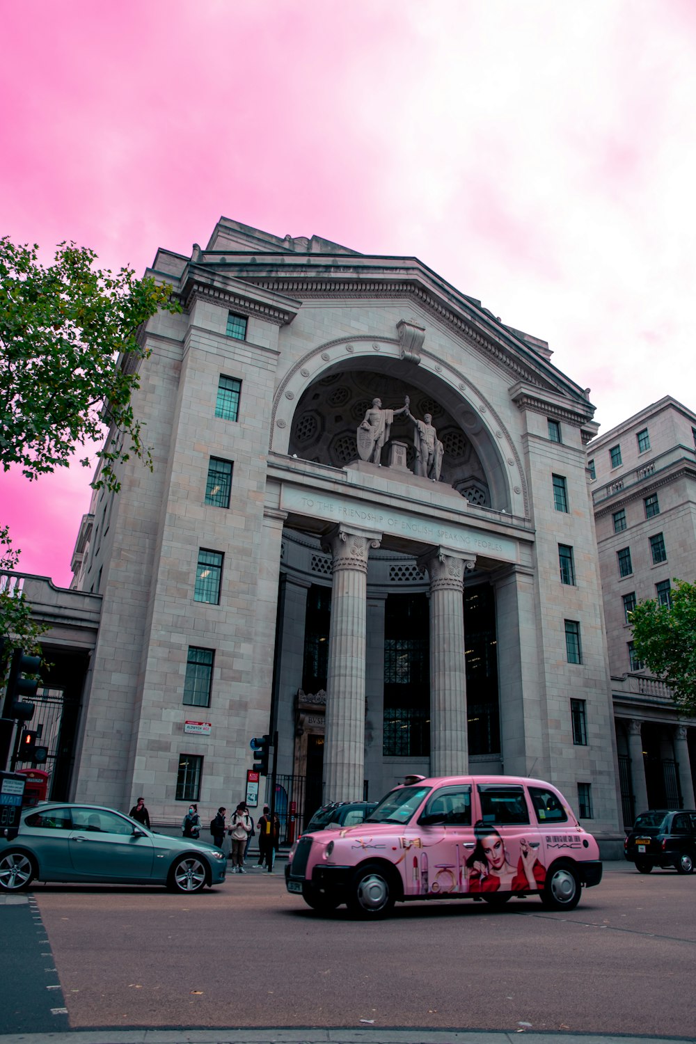 a pink car parked in front of a large building