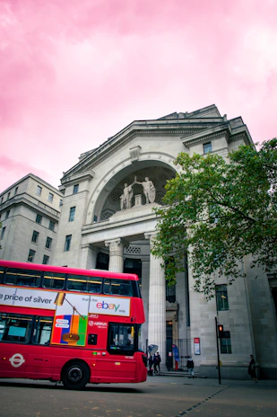 a red double decker bus parked in front of a building