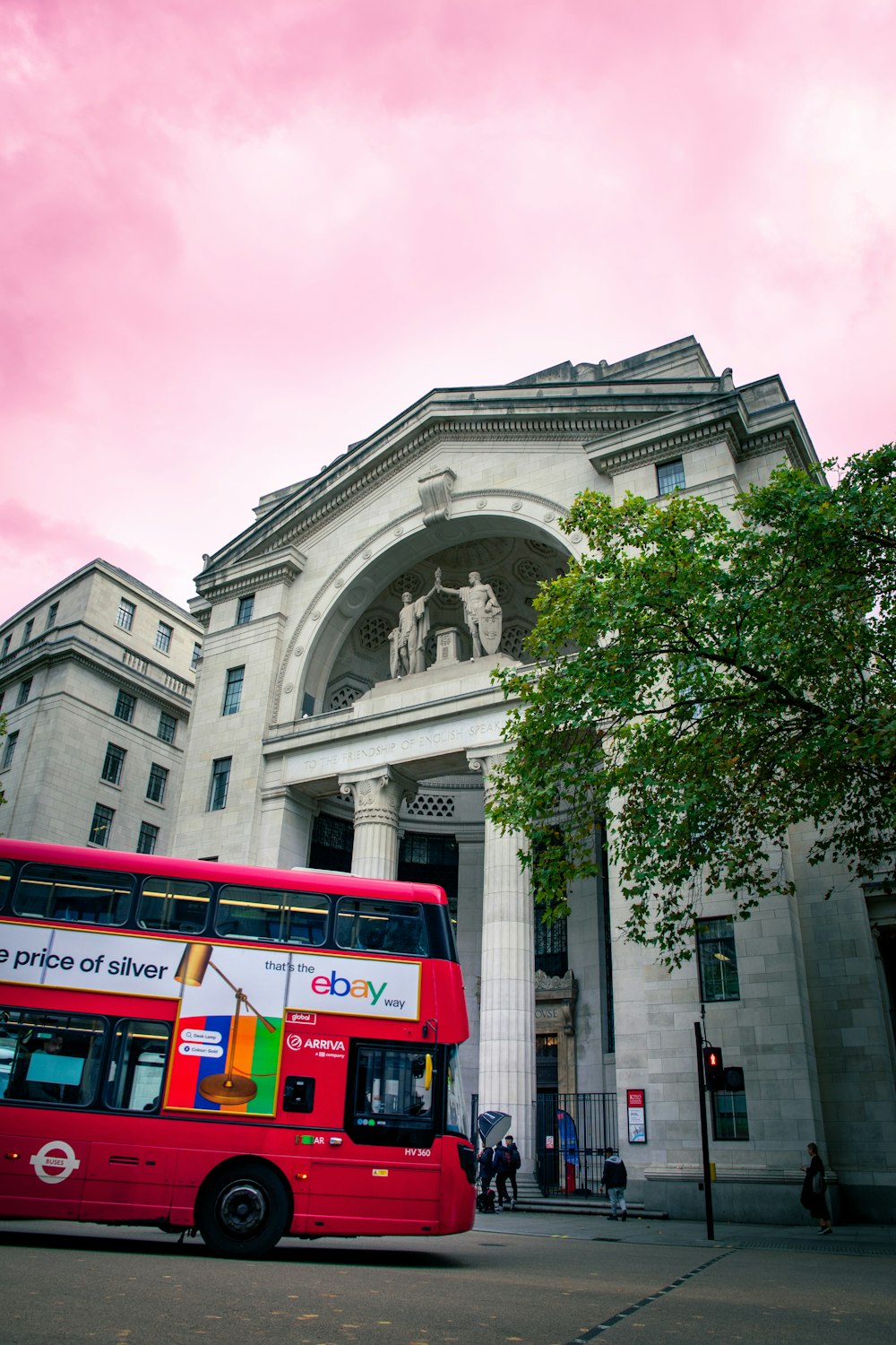 a red double decker bus parked in front of a building