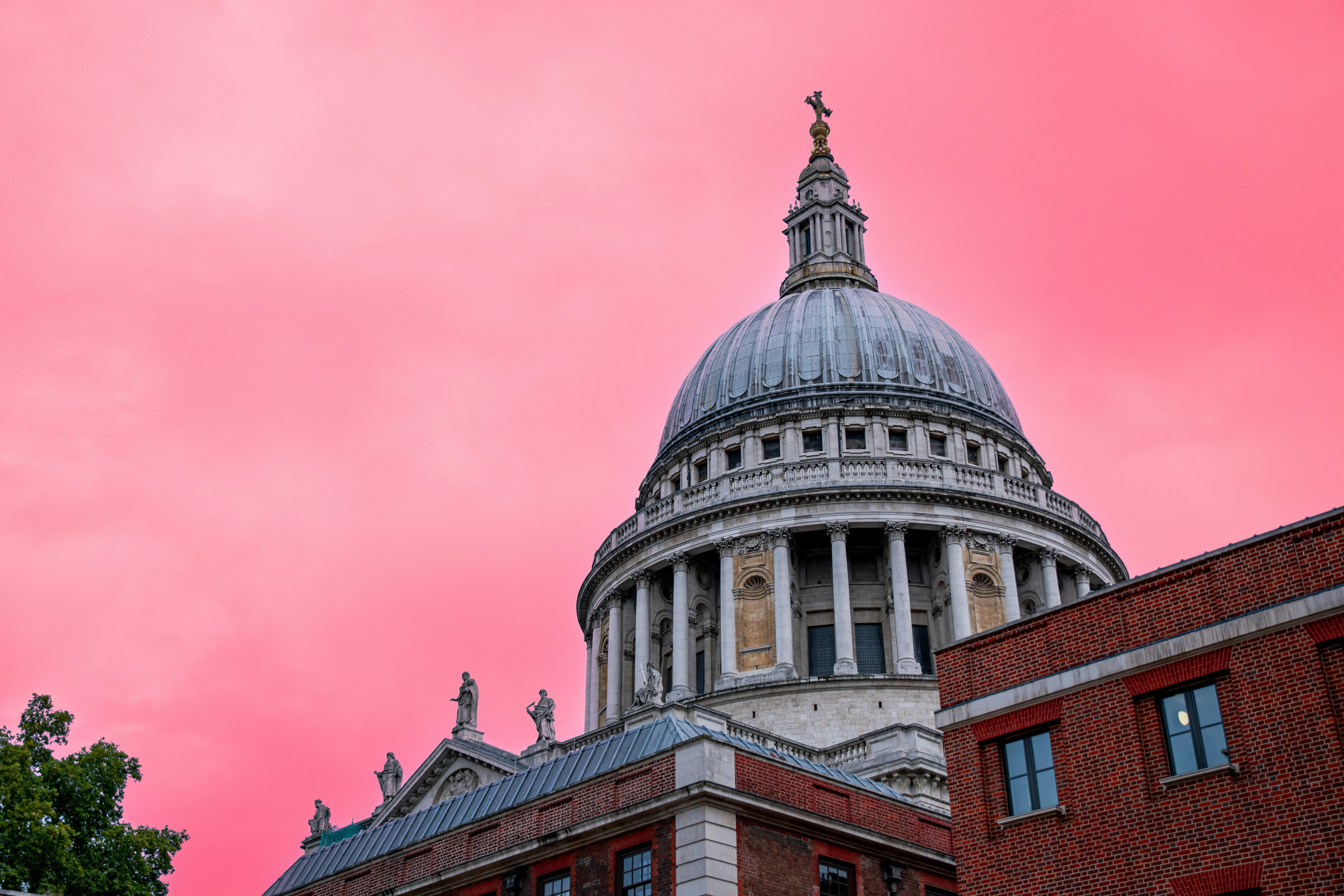 the dome of a building with a pink sky in the background