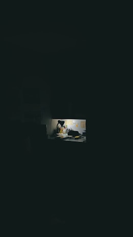 A minimalistic desk with a flickering candle and scattered papers.