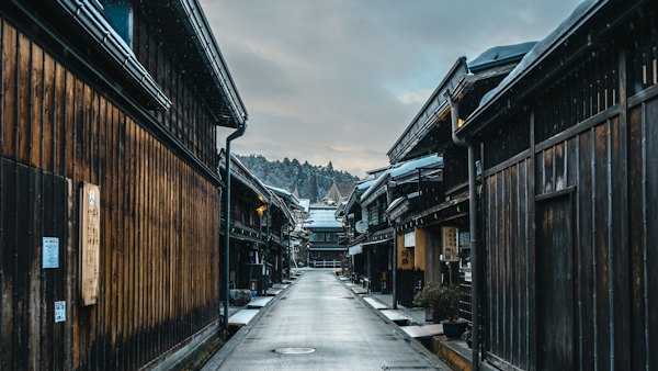 A narrow street with wooden buildings and snow on the ground — Takayama, Japan