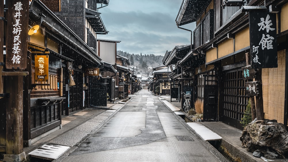 a narrow street in an asian city with snow on the ground