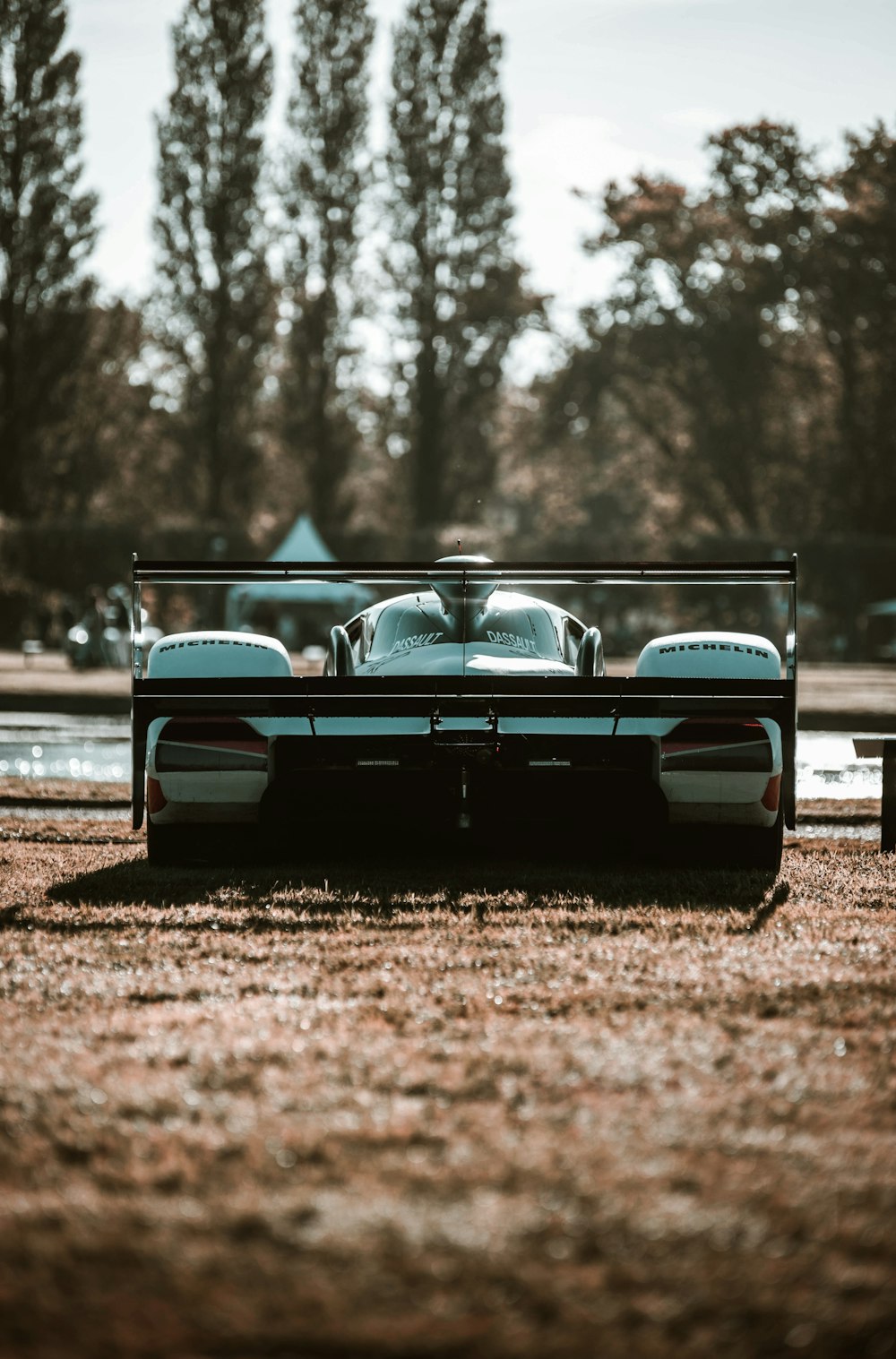 a car is parked in a field with trees in the background