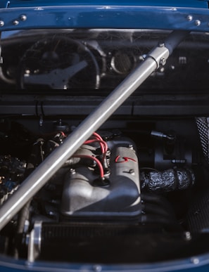 Close-up of a mechanic testing a car's wiring harness under the hood.