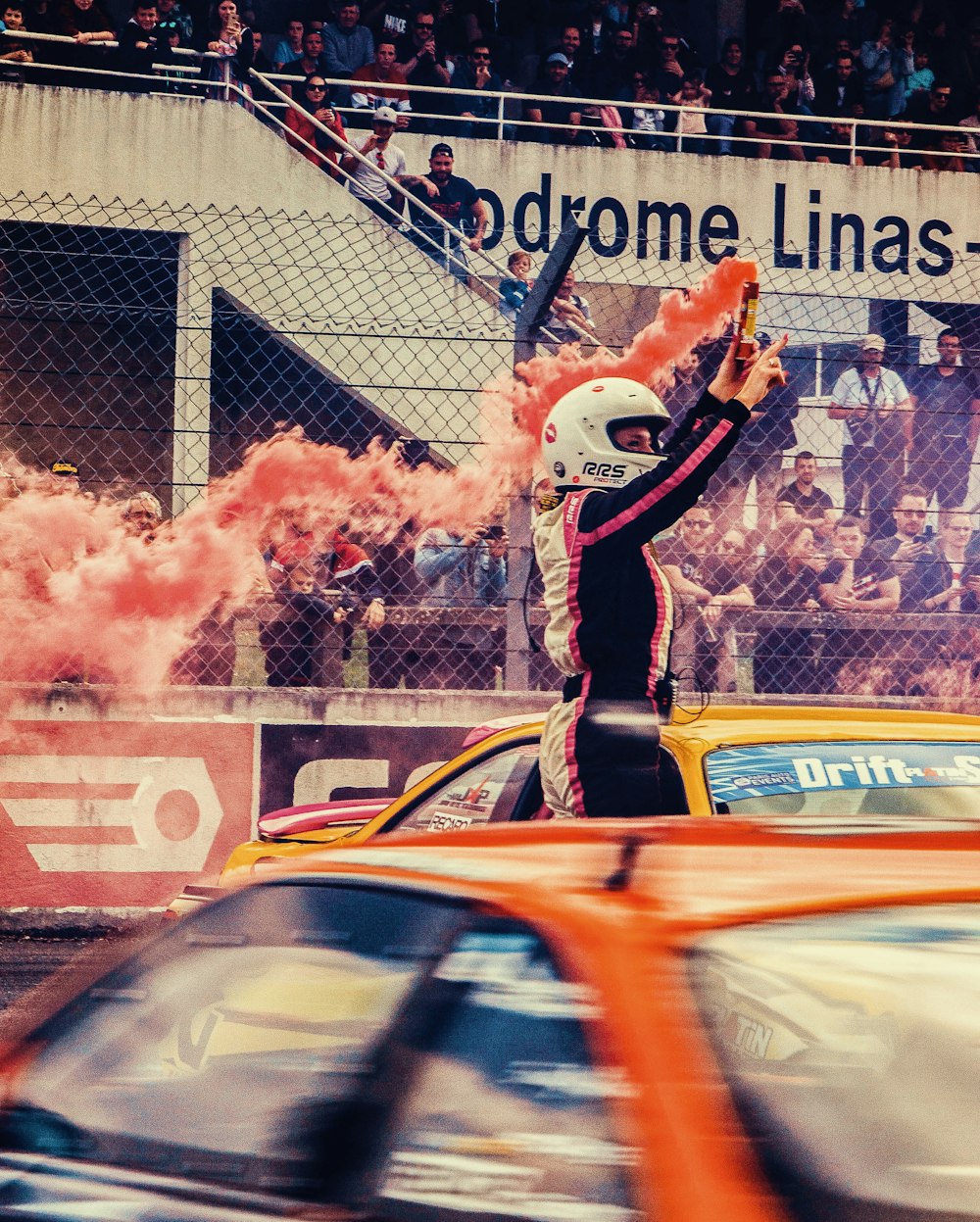 a man in a racing suit is waving to the crowd