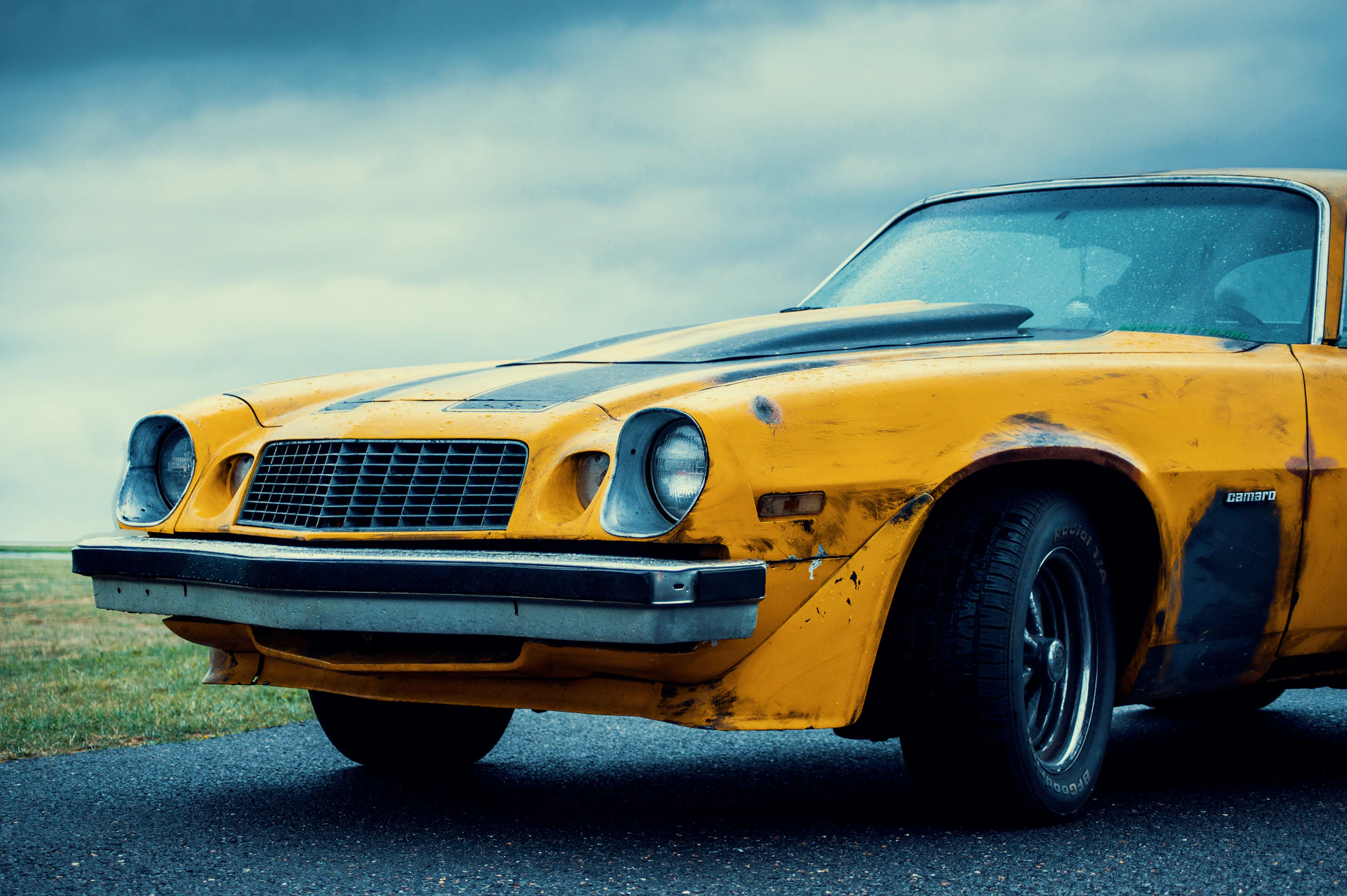 an old yellow car is parked on the side of the road