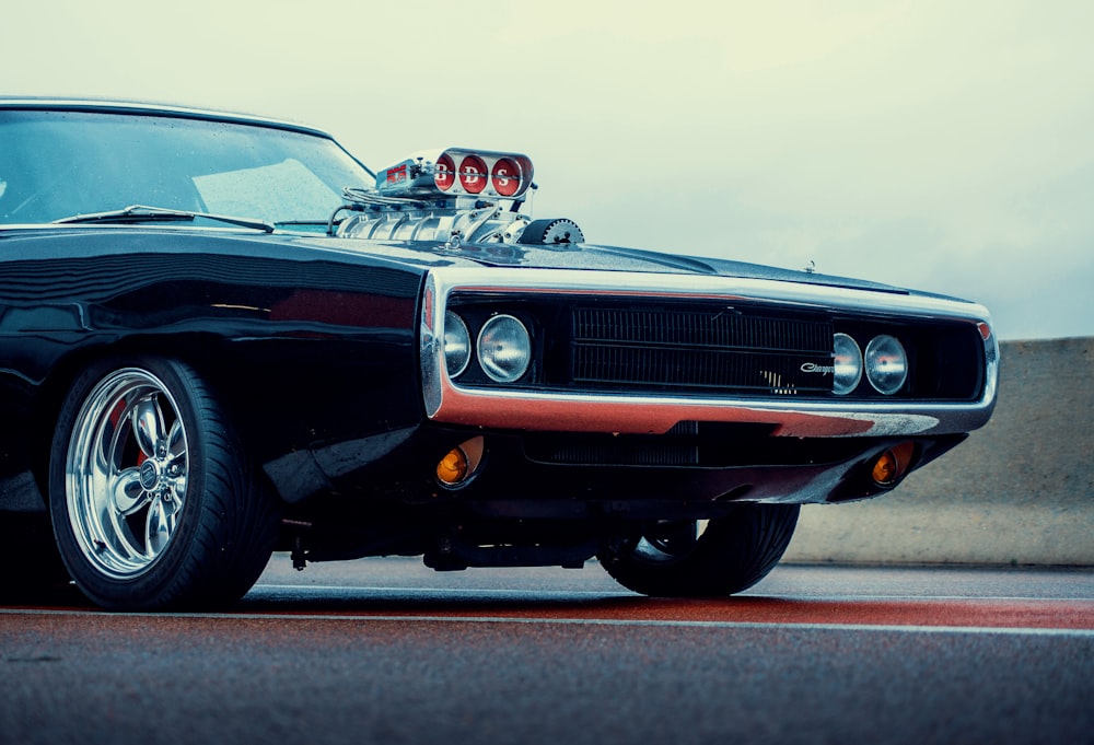 Un muscle car negro con llantas cromadas estacionado en la calle