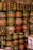 A collection of vibrant and intricately decorated ceramic pots and vases stacked on shelves. Each piece features unique patterns, including floral motifs, geometric designs, and colorful fish. The ceramics vary in size and shape, contributing to an eclectic and artistic display.