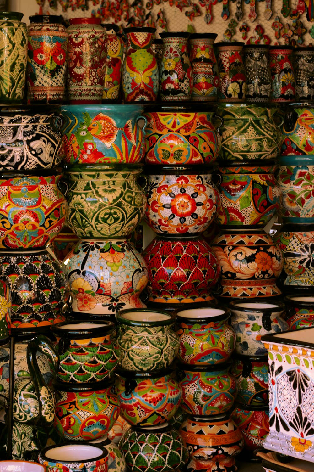 a wall full of colorful vases and bowls