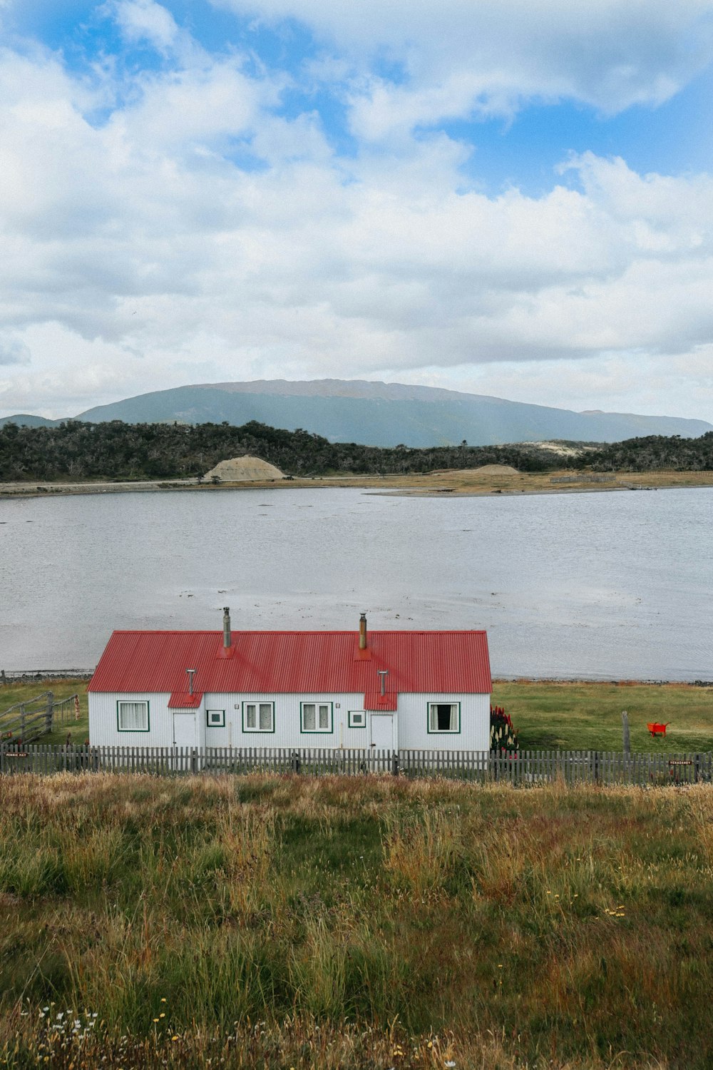 a white house with a red roof next to a body of water