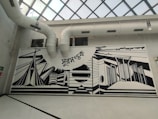 Artistic mural being painted on a large indoor wall.