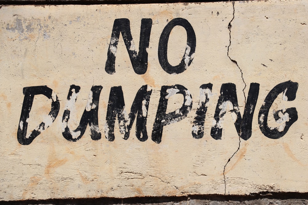 a no dumping sign painted on a wall