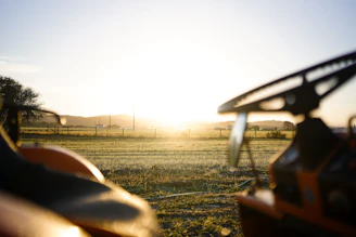 A peaceful rural landscape with crops and farm equipment at sunrise.