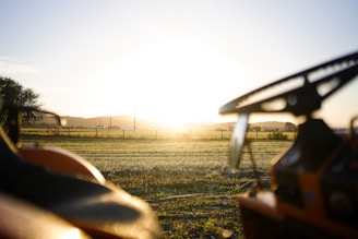 A tractor working the land at sunrise, with golden light illuminating the scene.