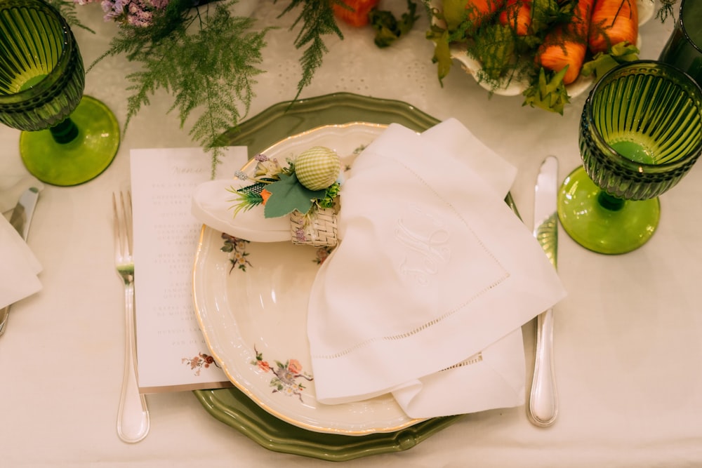 a table set with a plate, napkins, and green vases