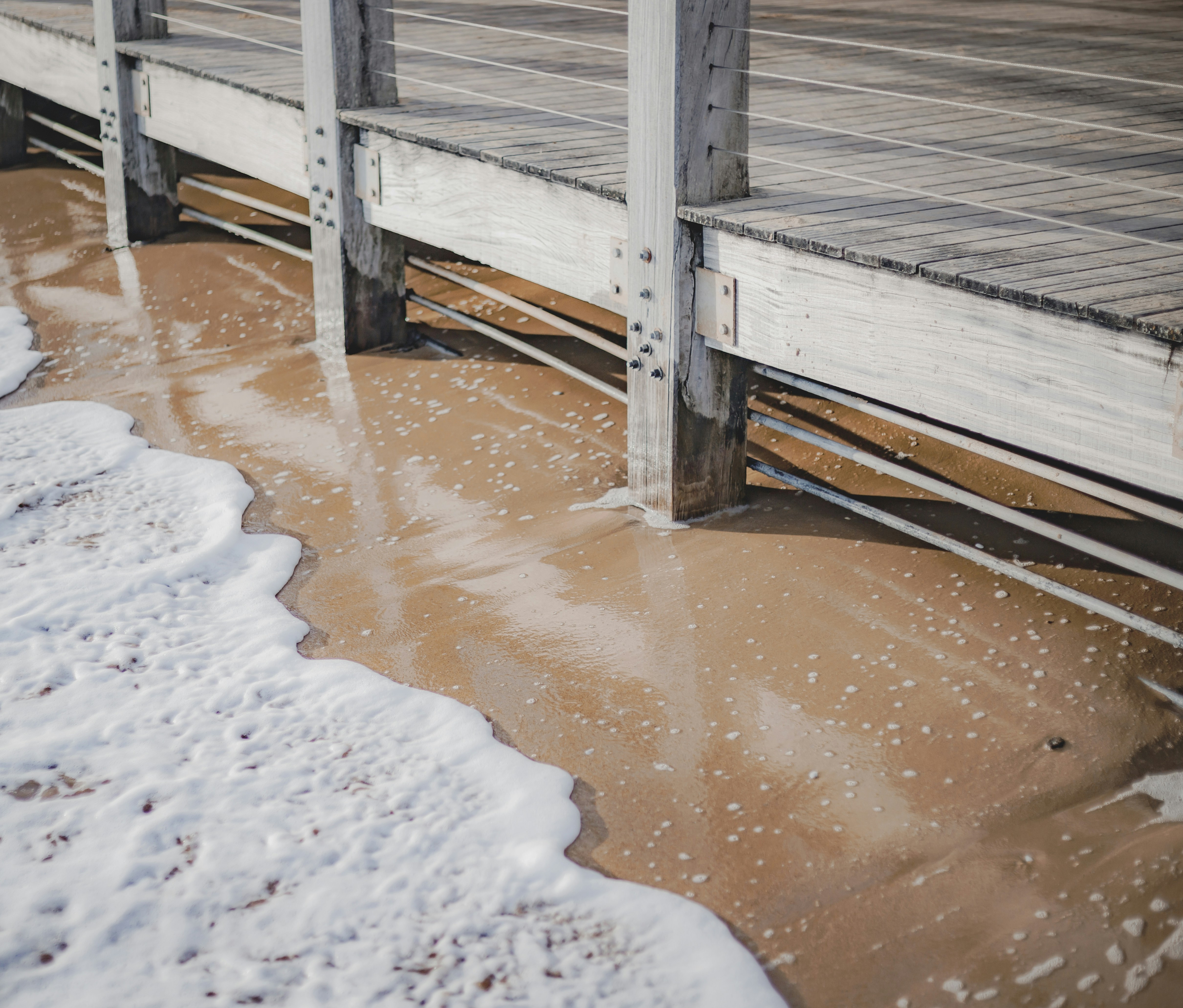 a wooden pier with water and snow on the ground
