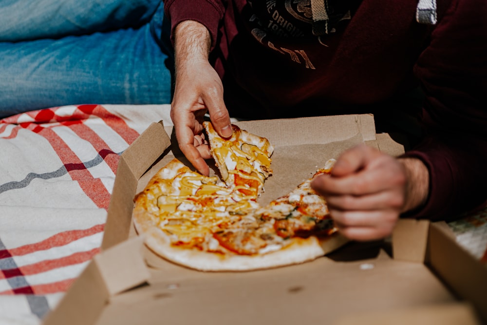 a person cutting a pizza in a box