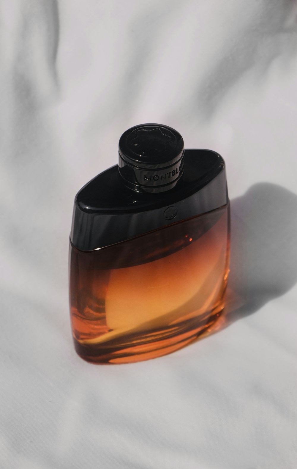 a bottle of perfume sitting on top of a white sheet
