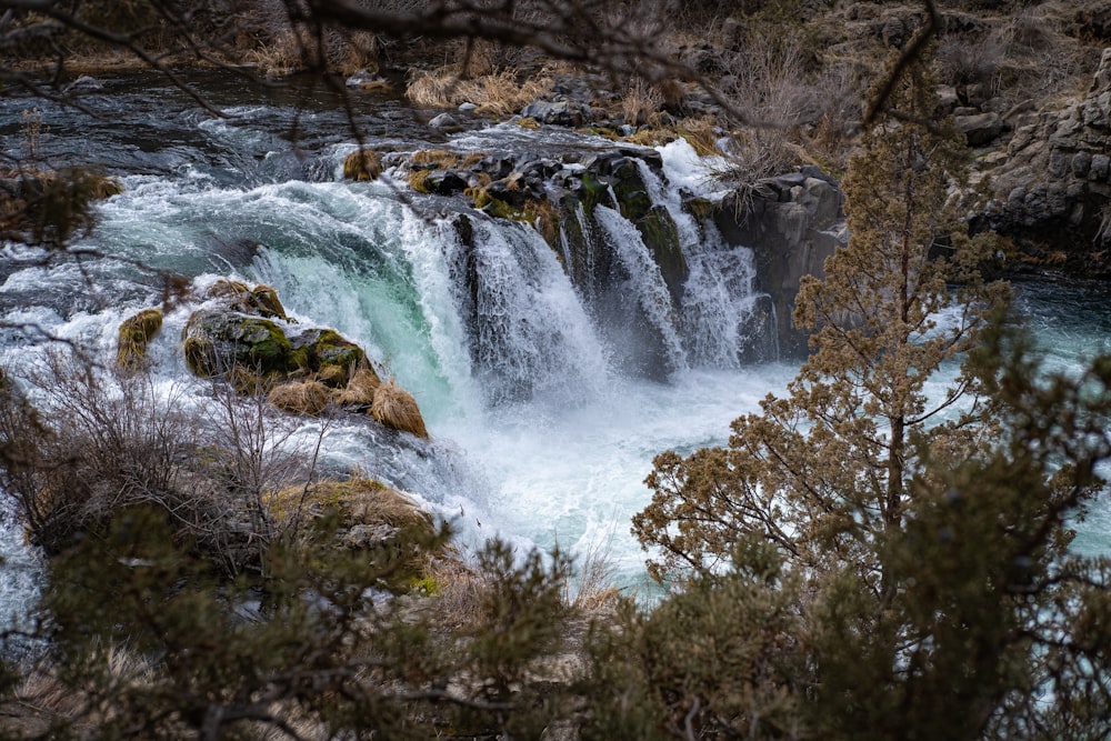 a waterfall with water flowing down it surrounded by trees