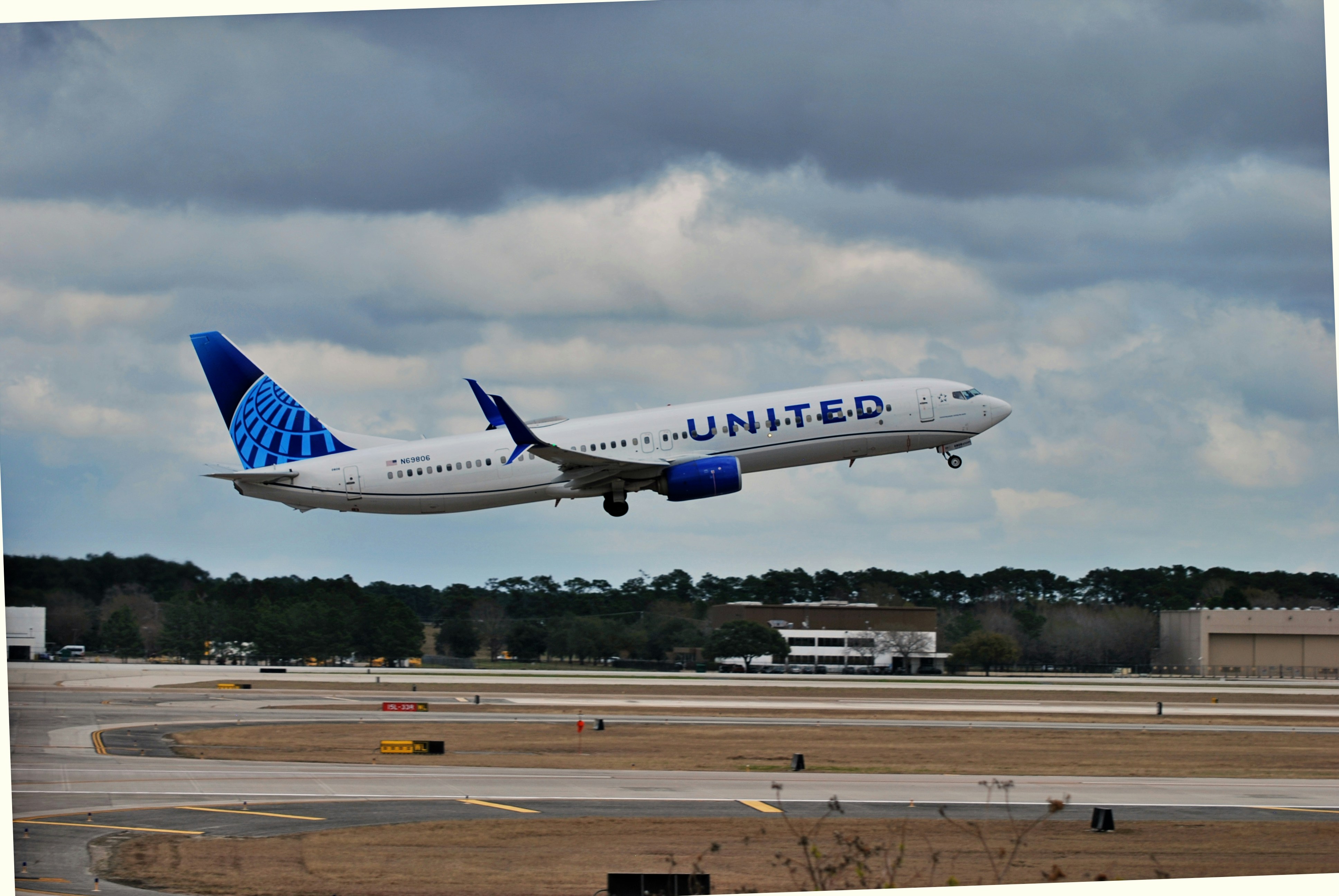 A large jetliner flying through a cloudy sky photo Free Iah terminal