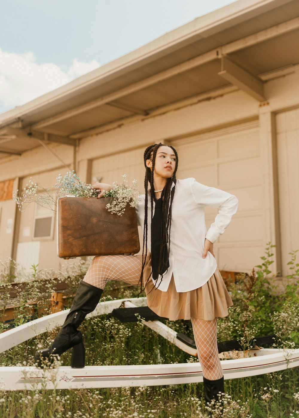 a woman in a white shirt and brown skirt holding a suitcase