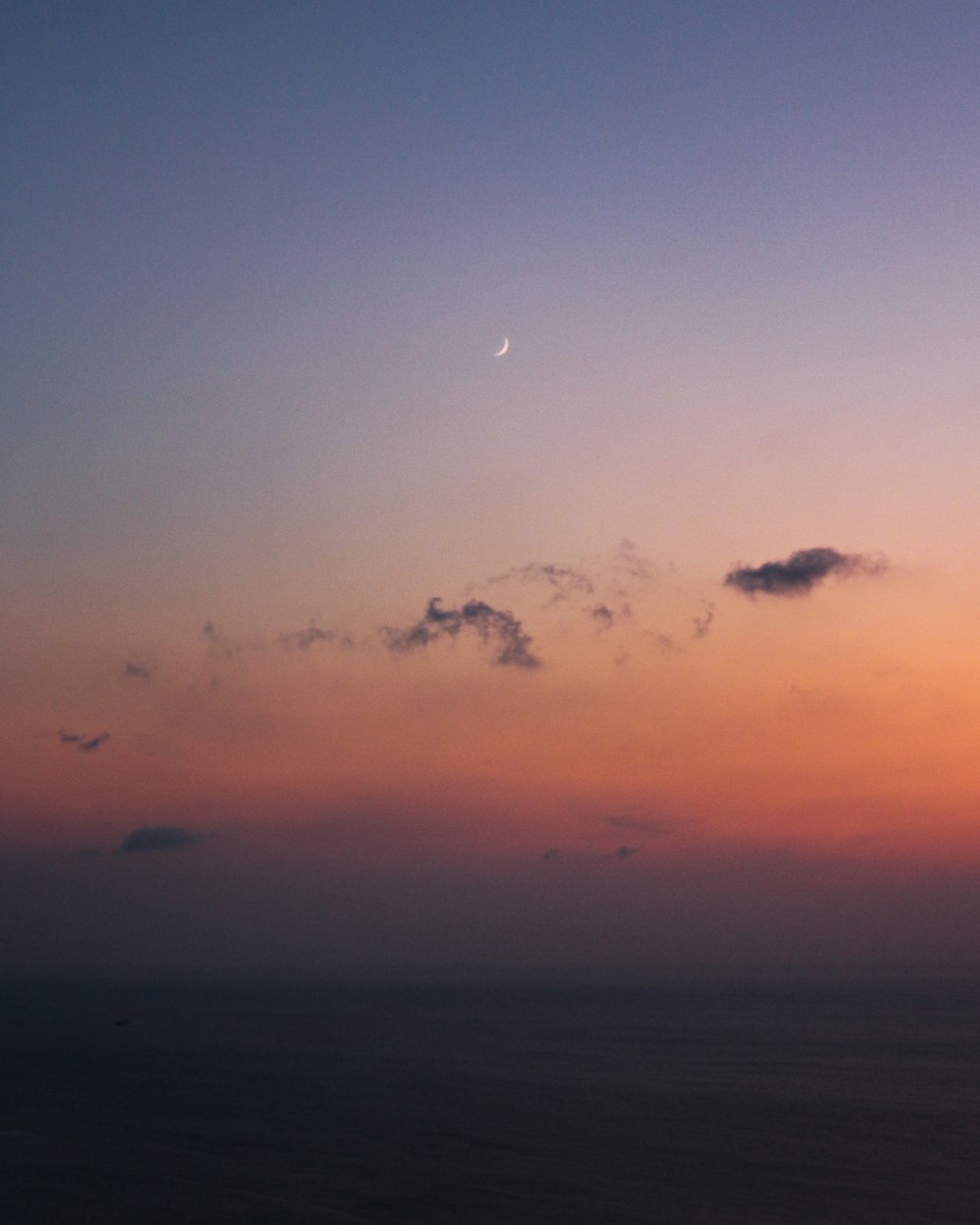 a plane flying in the sky at sunset