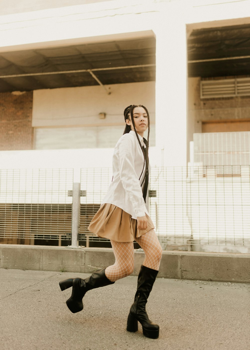 a woman walking down a street while wearing boots