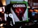 A video game case for the Xbox One sits prominently on a dark surface. The game is titled 'Control' and features a dramatic cover image of a character in a dynamic pose with a red and black color scheme. Surrounding the game case are various electronic gadgets and accessories, including headphones, coins, and a coiled cable.