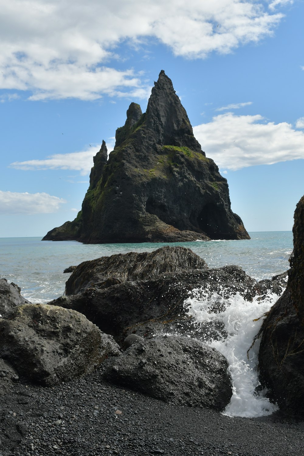 a rocky beach with a rock formation in the background
